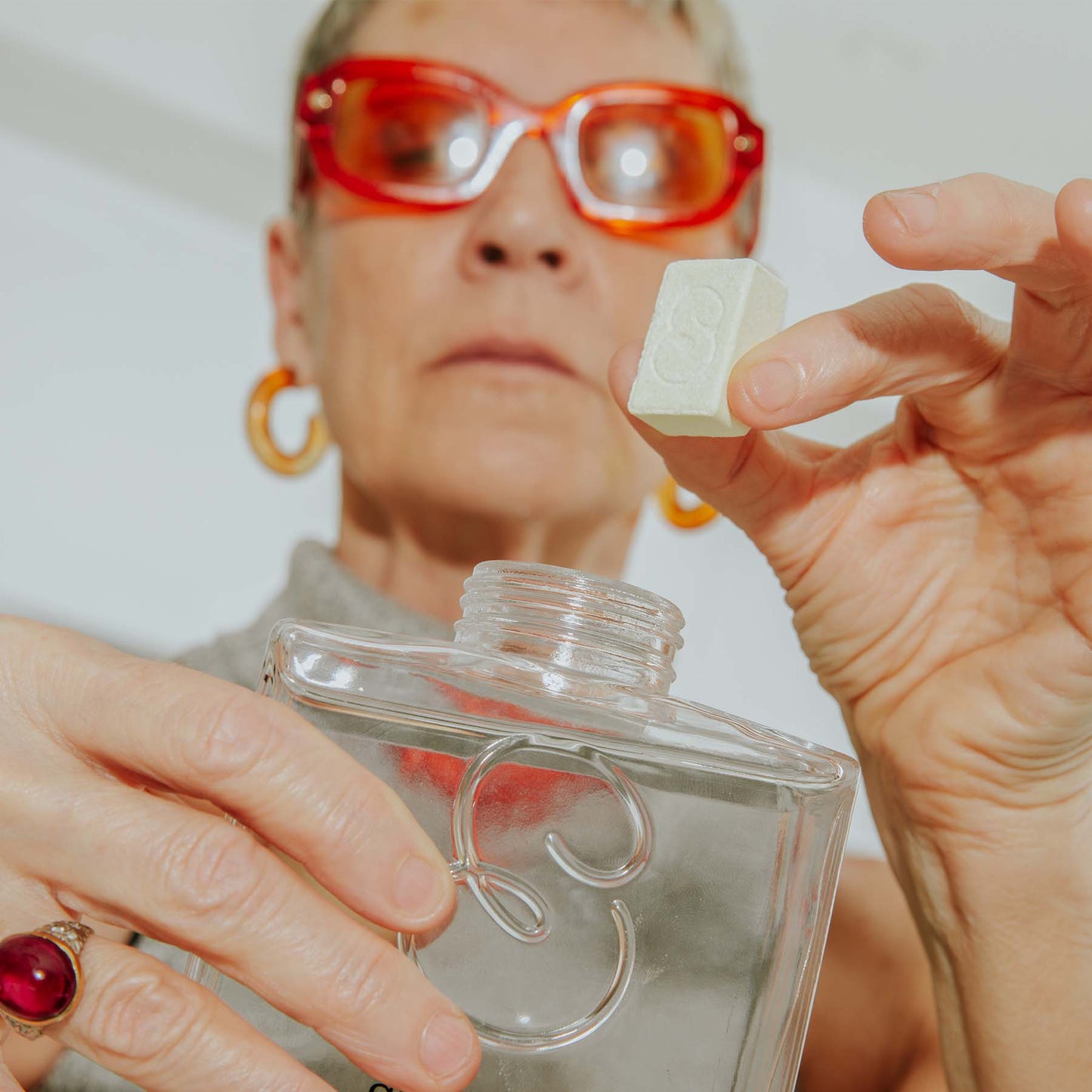 Lady dropping a hand wash tab into the hand wash glass bottle 250 ml